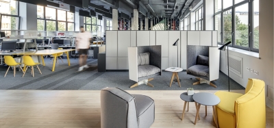 Biuro typu open space z grupą stołów roboczych i holem z fotelami