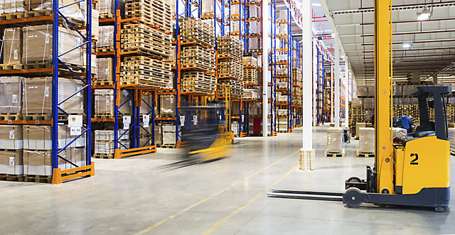 A busy warehouse with a yellow forklift in the forefront