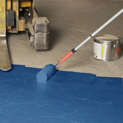 Applying blue garage floor paint with a paint roller