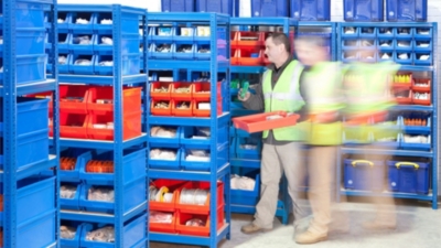 Warehouse worker collecting orders from picking bins on racking