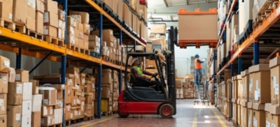Forklift operator works with stock in a large industrial warehouse