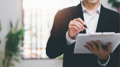 Business executive makes notes on a clipboard at head office
