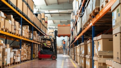 Warehouse workers using a forklift and warehouse steps to load racks