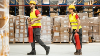 Warehouse staff carry fire extinguishers as part of fire safety training