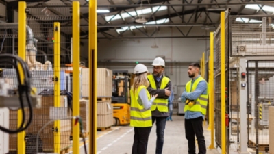 Staff in hi-vis jackets and PPE discuss warehouse health and safety